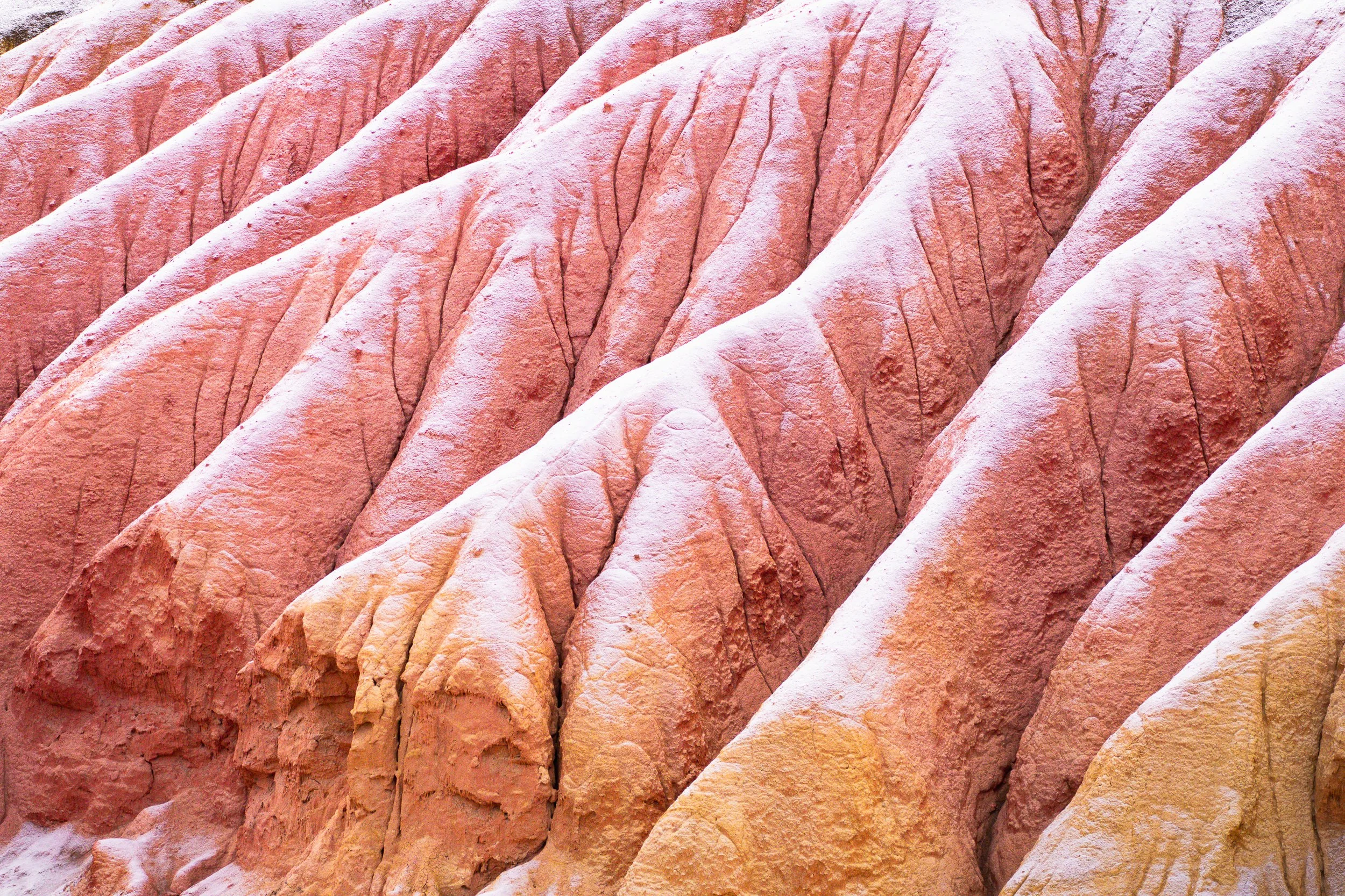 Close-up view of pinkish-red layered rock formations with distinct creases and rugged textures.