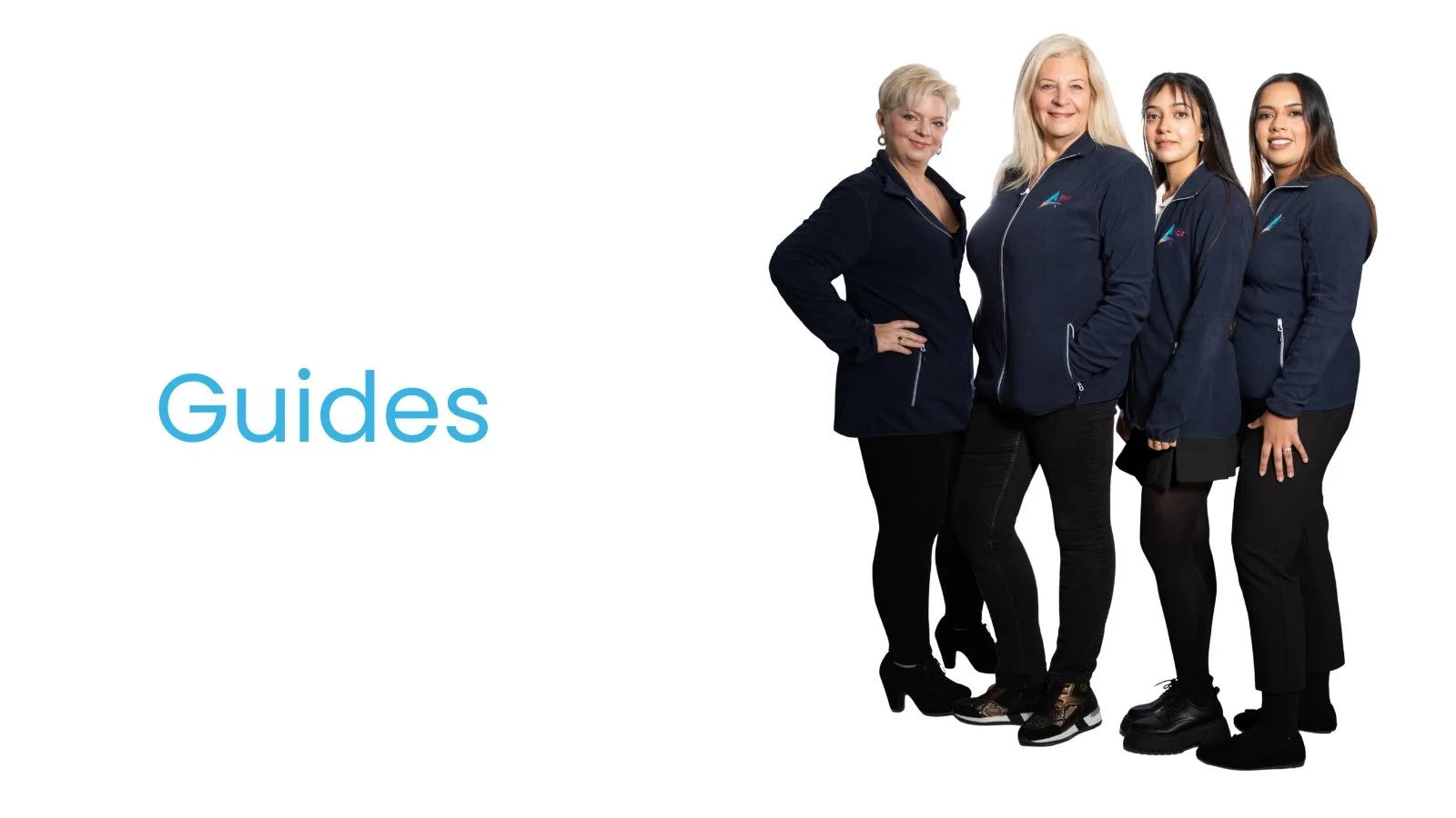 Group of four women standing together, wearing matching navy jackets with a logo, smiling, on a white background with the word 'Guides' in blue text.