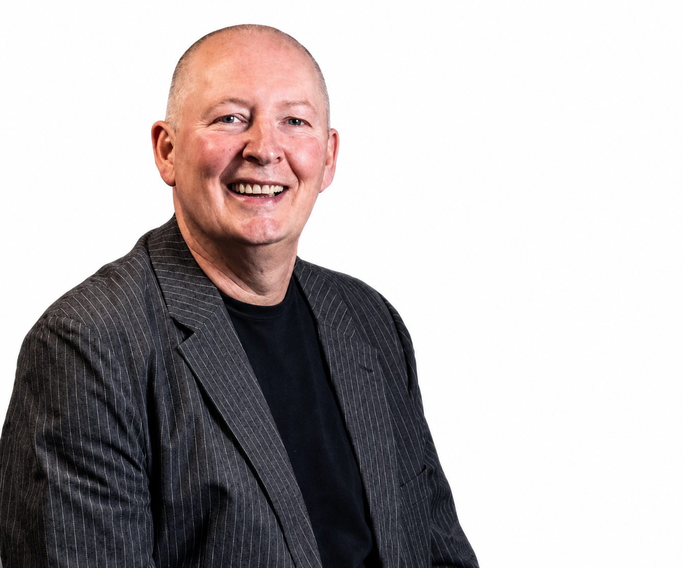 Portrait of a smiling bald man in a black shirt and dark pinstripe blazer against a white background.