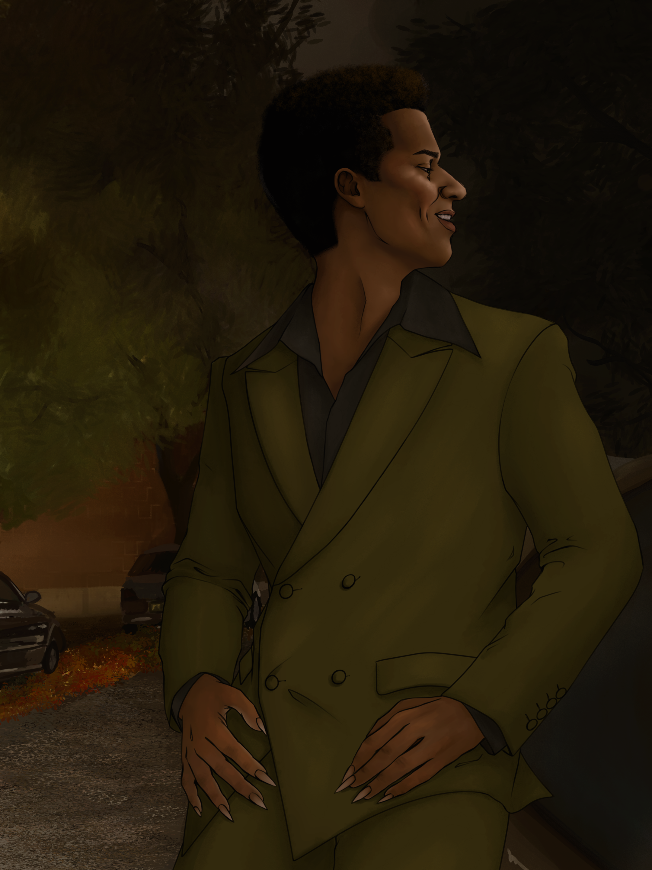 A person with short curly hair and painted long nails, wearing a green double-breasted suit, standing outdoors with trees and cars in the background.