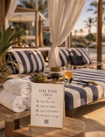 Poolside cabanas with striped cushions, a day pass sign, and drinks on a table at a resort.