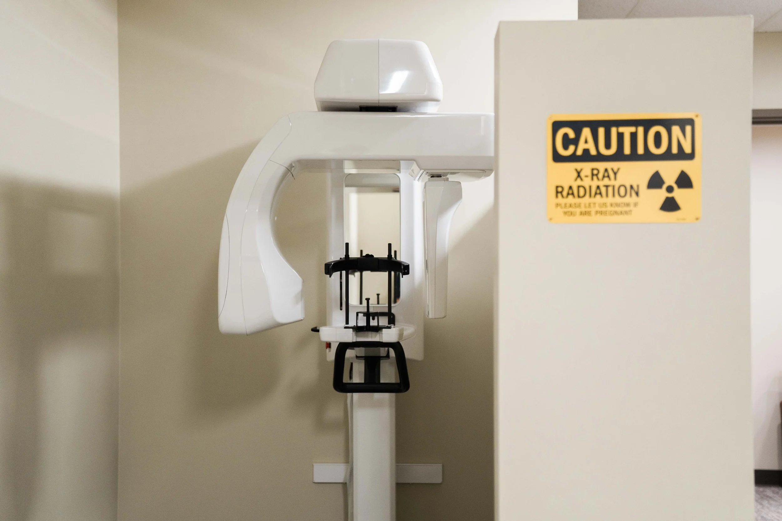 Medical X-ray machine in an examination room with a caution sign warning about X-ray radiation