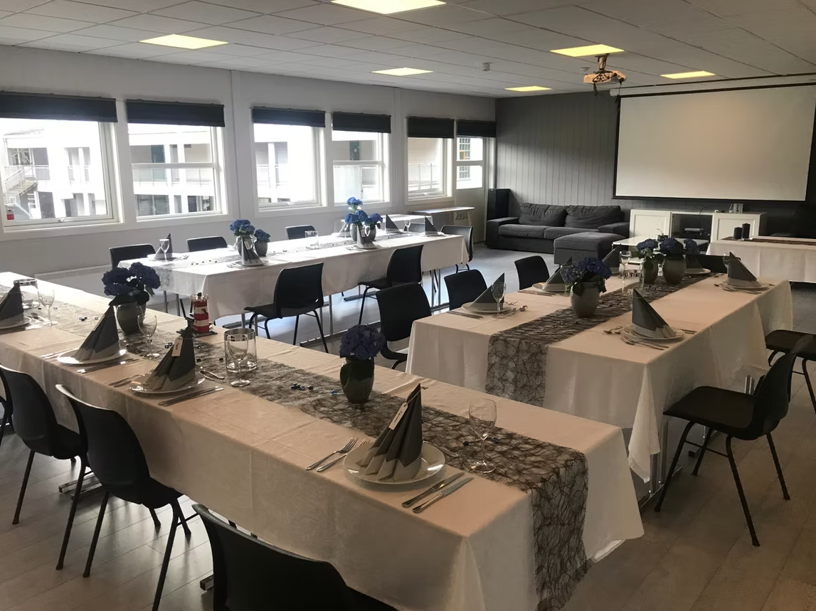 Dekket bord med blomster og plass til middag i et møterom eller selskapslokale.