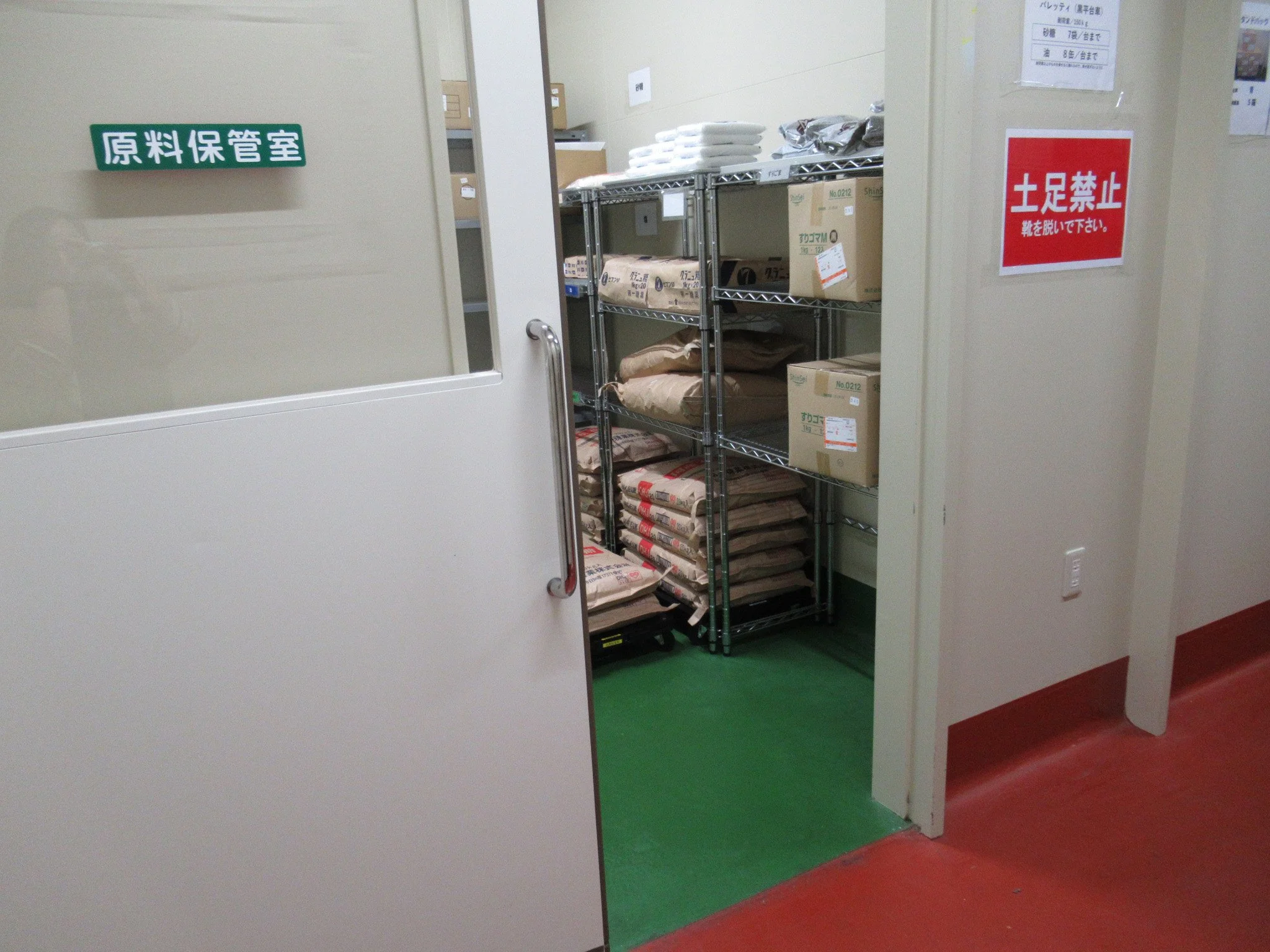 工場の一角にある原料保管室の内部の写真。棚には粉状や袋詰めされた原料が整然と並べられている。