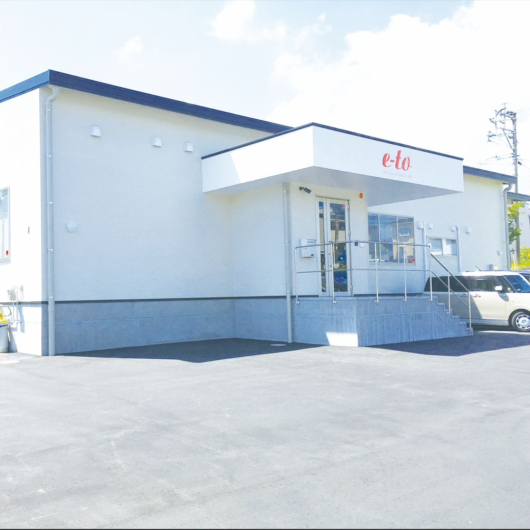 白い建物の外観で、pとなっている看板があり、入り口に階段と手すりが付いている。