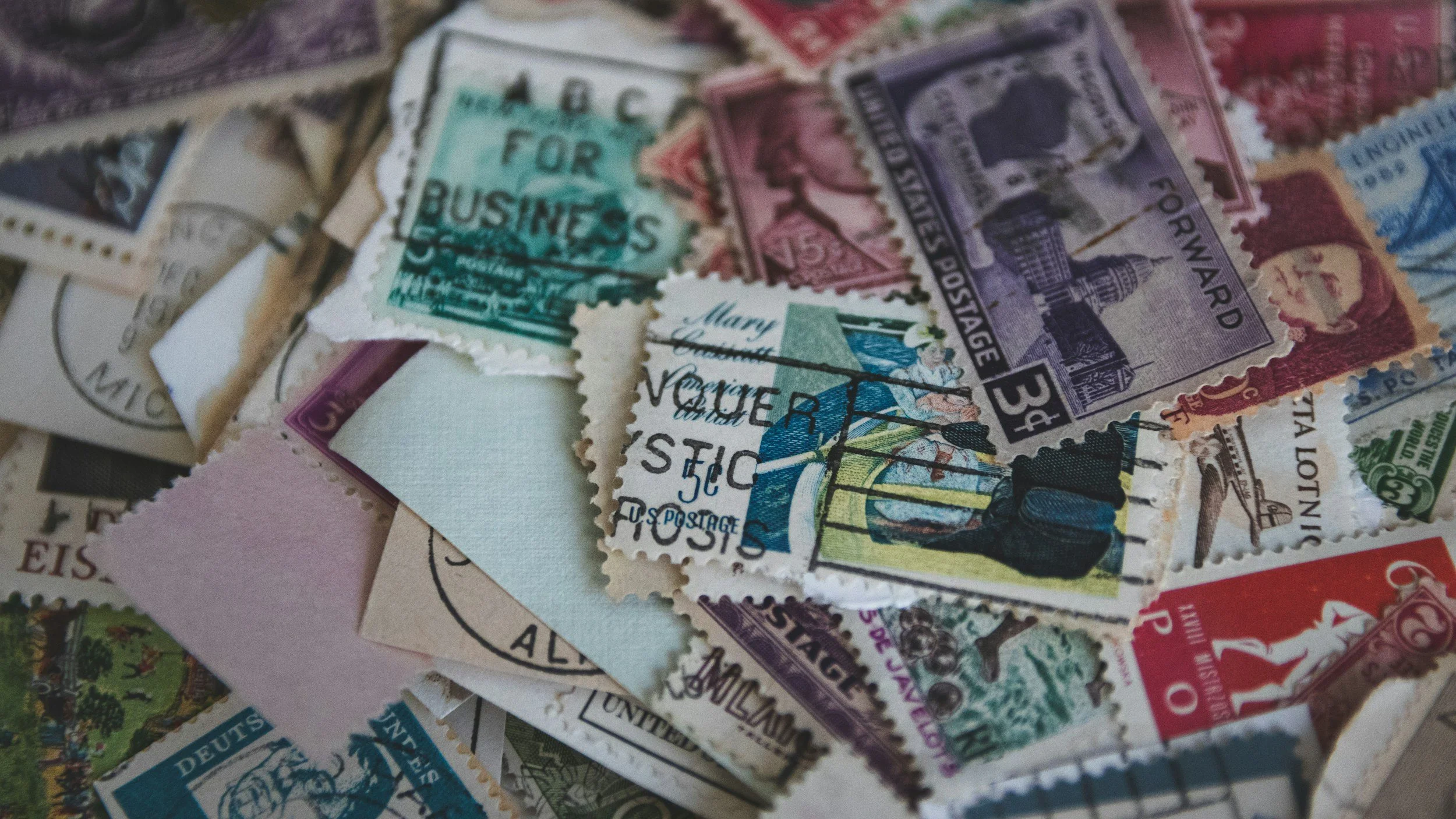 A collection of vintage postage stamps from various countries, some overlapping each other, in different colors and sizes.