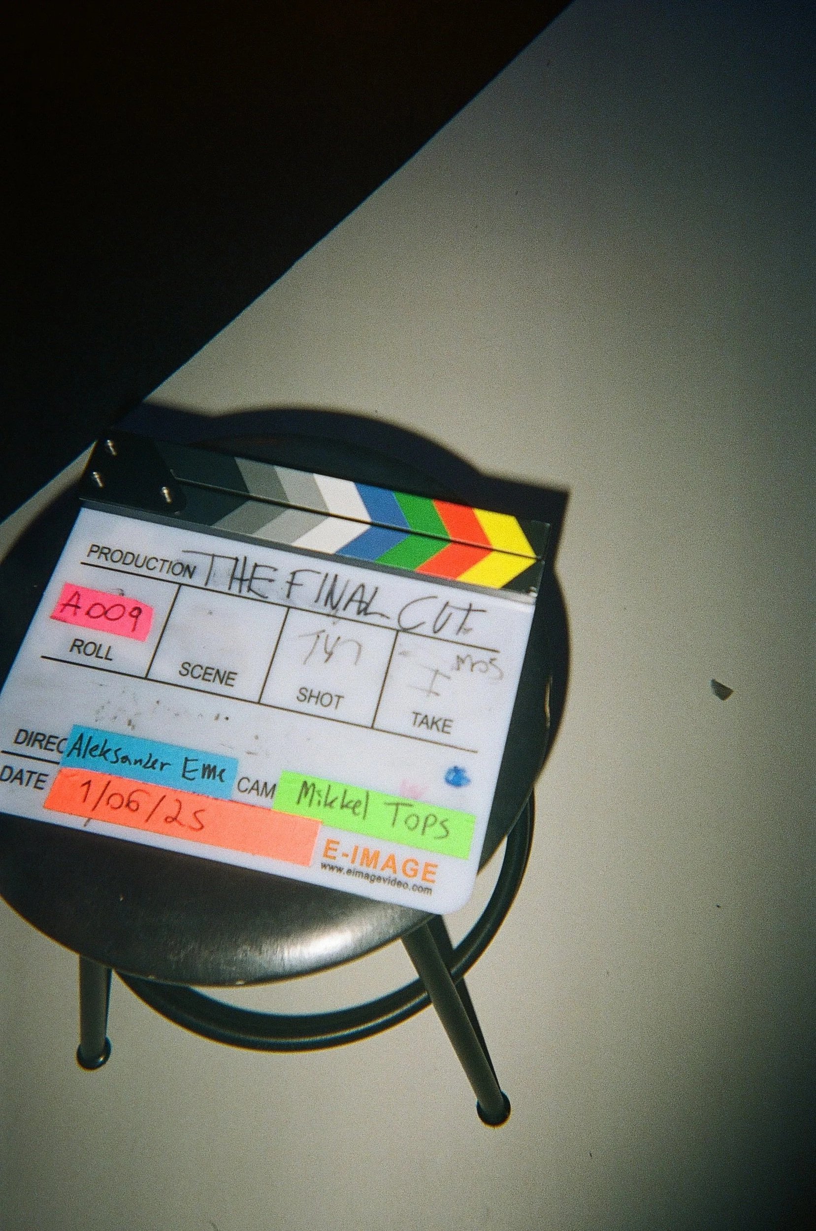 Clapperboard titled 'The Final Cut' with handwritten notes and colored labels, placed on a black stool.