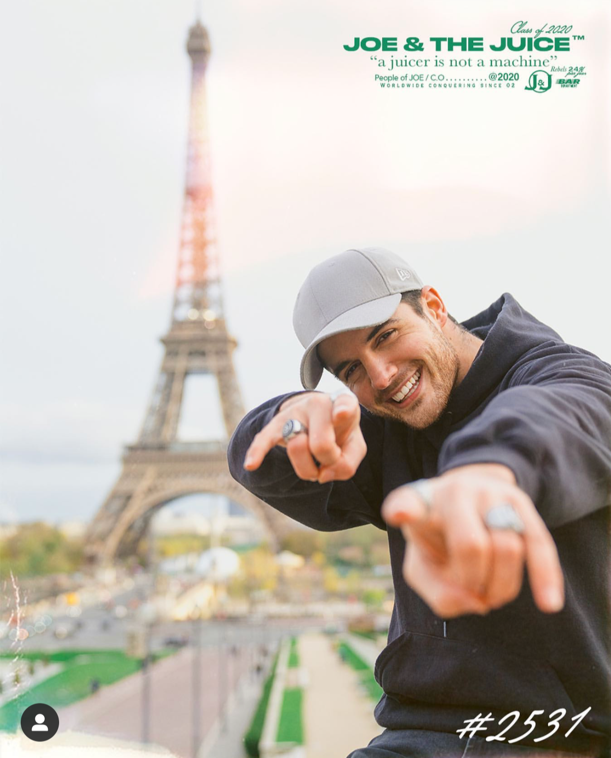 Young man smiling and pointing at the camera with the Eiffel Tower in the background in Paris, France.