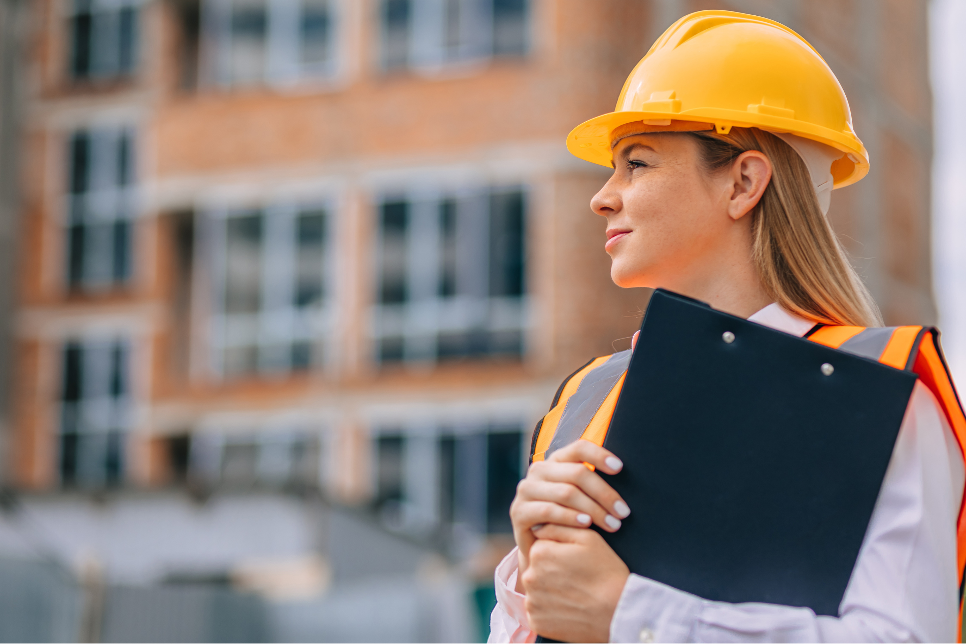 Woman wearing full PPE, including a hard hat and high-visibility jacket, working on electrical infrastructure in the power utilities sector.