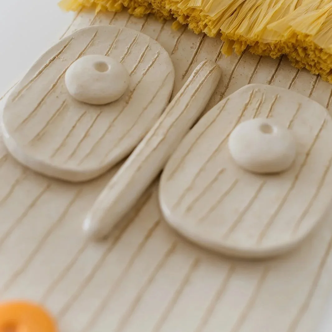 Solara handmade ceramic wall mask with natural raffia fringe and expressive orange lips detail