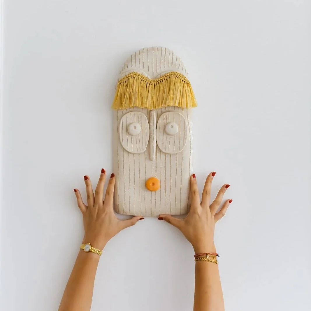 Solara handmade ceramic wall mask with natural raffia fringe and expressive orange lips detail