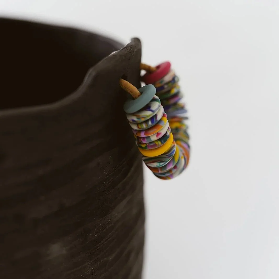 Noir handmade black pottery vase with textured finish and vibrant colorful rings
