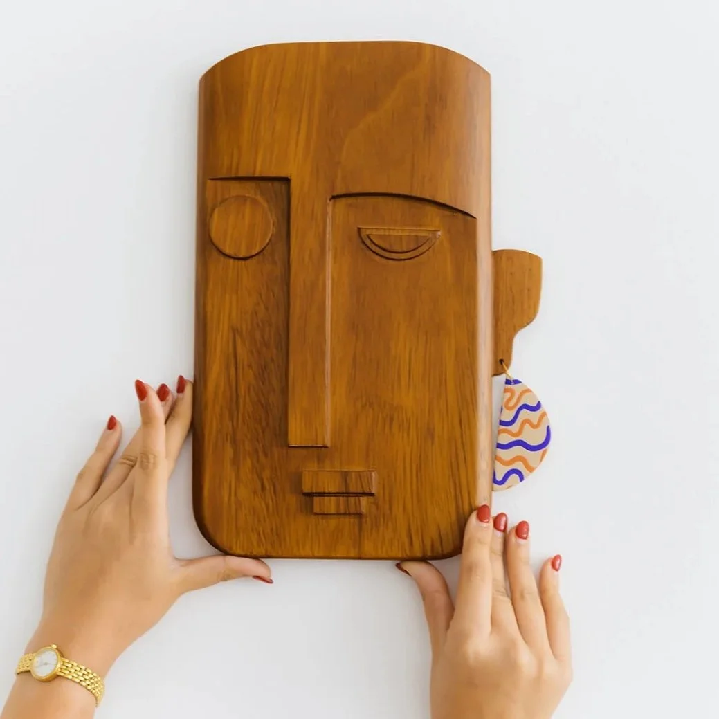 Zaira hand-carved Kambala wood mask featuring a unique single earring and minimalist facial features