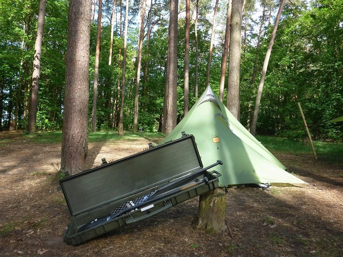 Explorer-koffert ved telt i skogsterreng, brukt til robust transport av utstyr i felt.