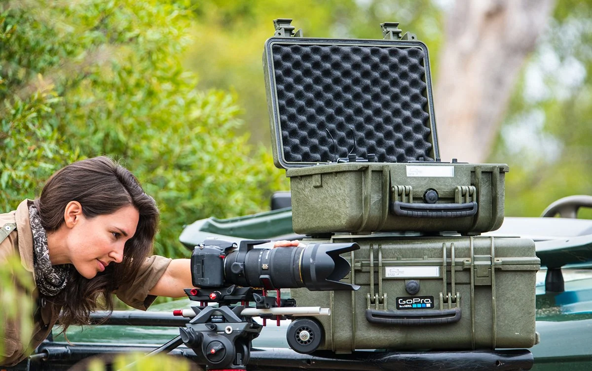 Kvinnelig fotograf i felt med Explorer Cases utstyrskofferter.