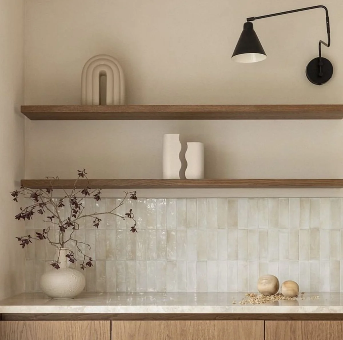 Modern living room with a round dining table, four upholstered chairs, large window with white curtains, a gray sofa, framed artwork, indoor plants, and wooden flooring.