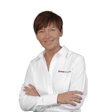 Frau in weißem Hemd mit InnoGreen-Logo, lächelnd mit verschränkten Armen