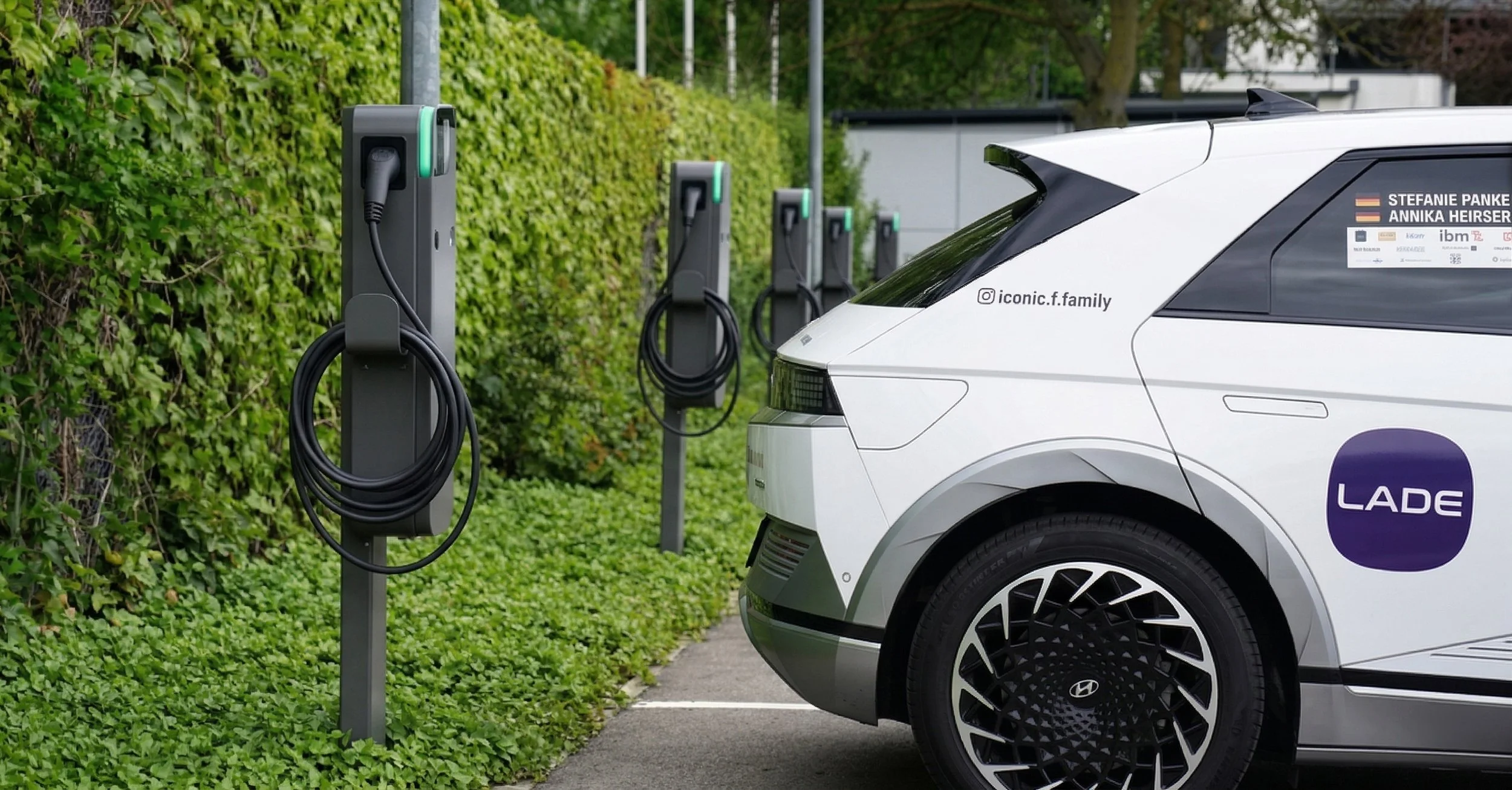 Ein weißes Elektroauto ist an einer Ladestation mit mehreren Ladepunkten zum Aufladen von Elektrofahrzeugen angeschlossen.