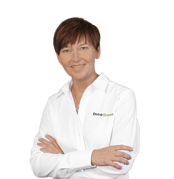 Frau trägt weiße Jacke mit InnoGreen-Logo, lächelnd, Arme verschränkt