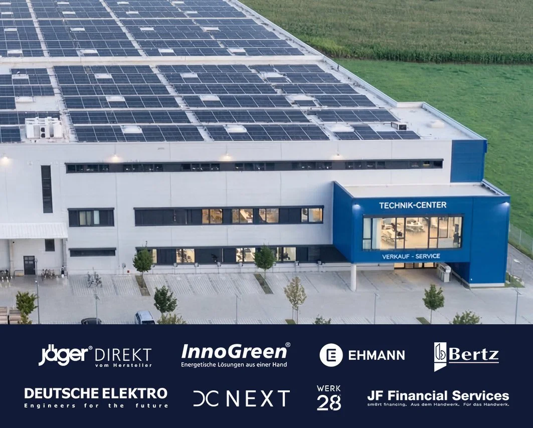 Das Bild zeigt ein modernes Technik-Center mit Solarzellen auf dem Dach, umgeben von grünen Feldern. Am Gebäude sind Firmenlogos und die Bezeichnungen "TECHNIK-CENTER" und "VERKAUF - SERVICE" sichtbar.