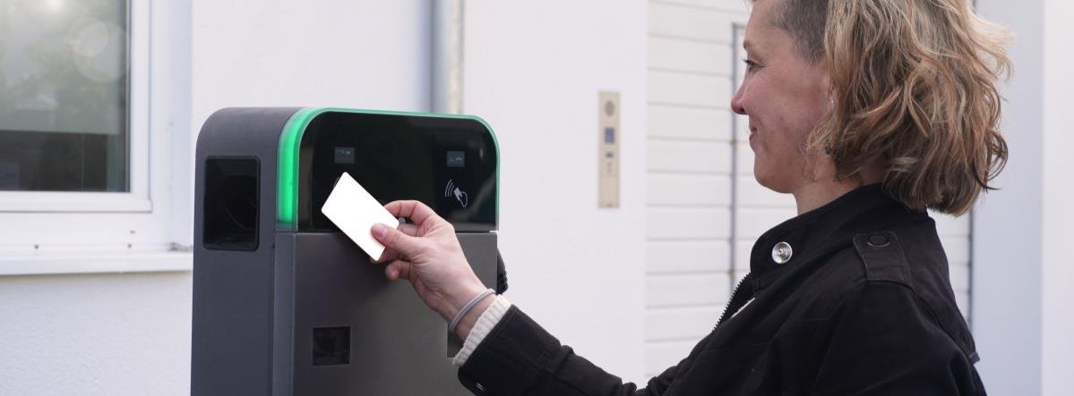 Frau benutzt ein kontaktloses Bezahlsystem an einem Automaten.