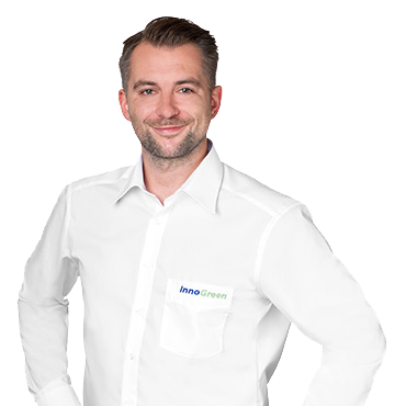 Ein Mann trägt ein weißes Hemd mit einem Namensschild, das 'InnoGreen' heißt, und lächelt.