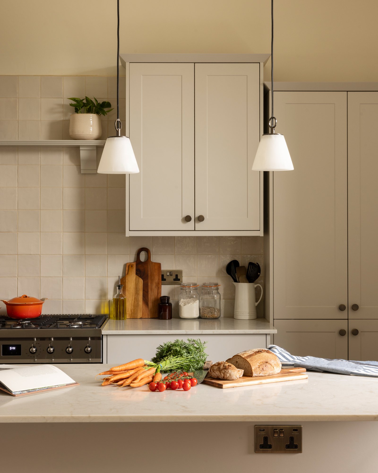 Kitchen scene with vegetables, bread, a cookbook, and a stove.