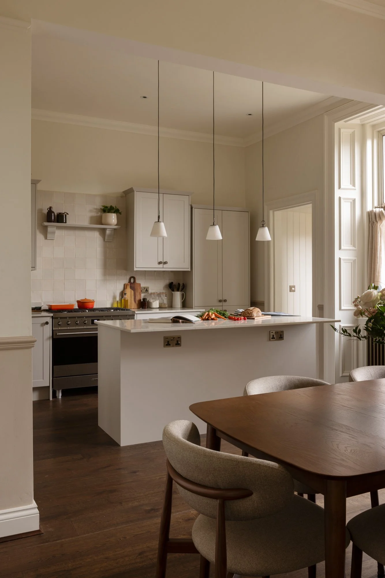 Modern kitchen with white cabinets, pendant lighting, and a kitchen island with food, in an open plan dining and living area.