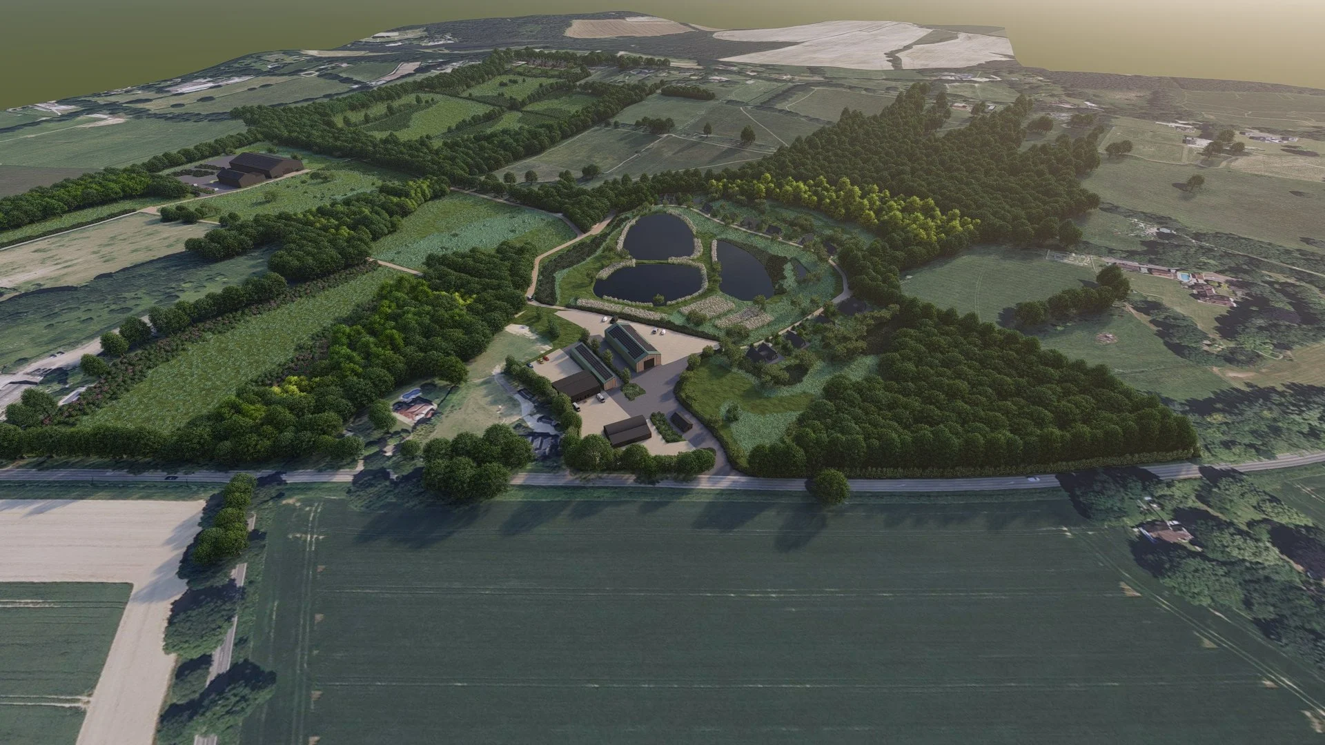 Aerial view of a large landscaped park with ponds, walking paths, surrounded by trees and farmland, and some buildings nearby.