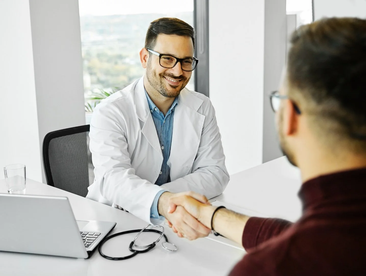 Medical professional shaking his hand with a perspective patient.