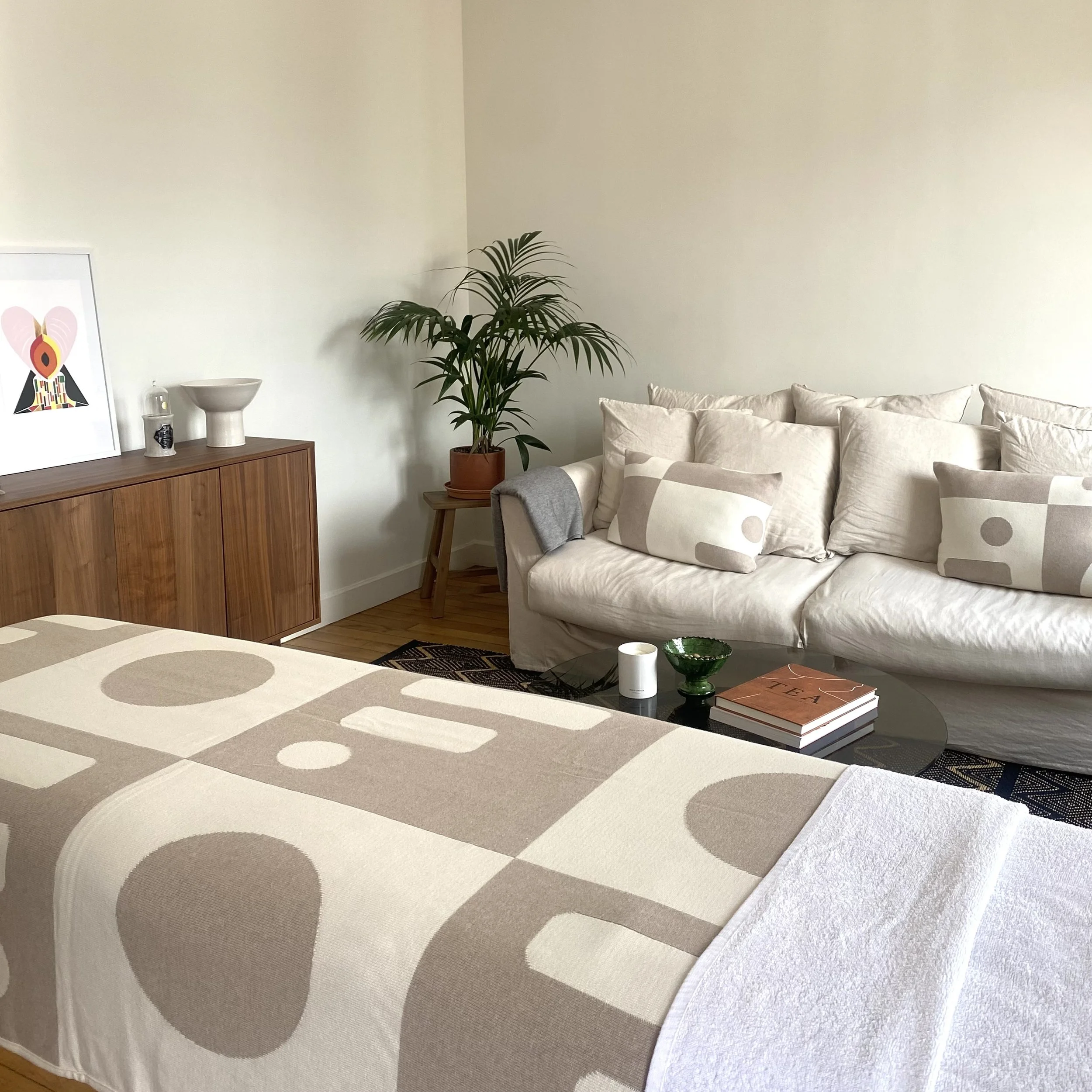 Un tapis moderne à motifs de cercles dans des tons de beige, brun et blanc, dans un salon avec un canapé blanc et une table en verre.