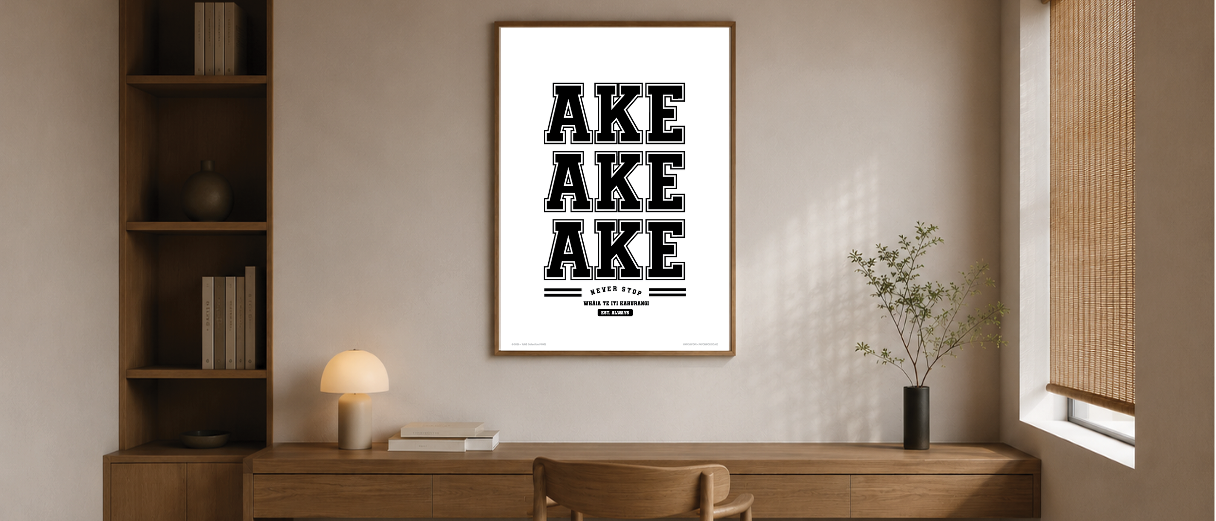 Wall art with the word 'AKE' repeated three times in large black letters, with smaller text underneath that says 'Never stop waha te iti kawharang,' in a modern living room.