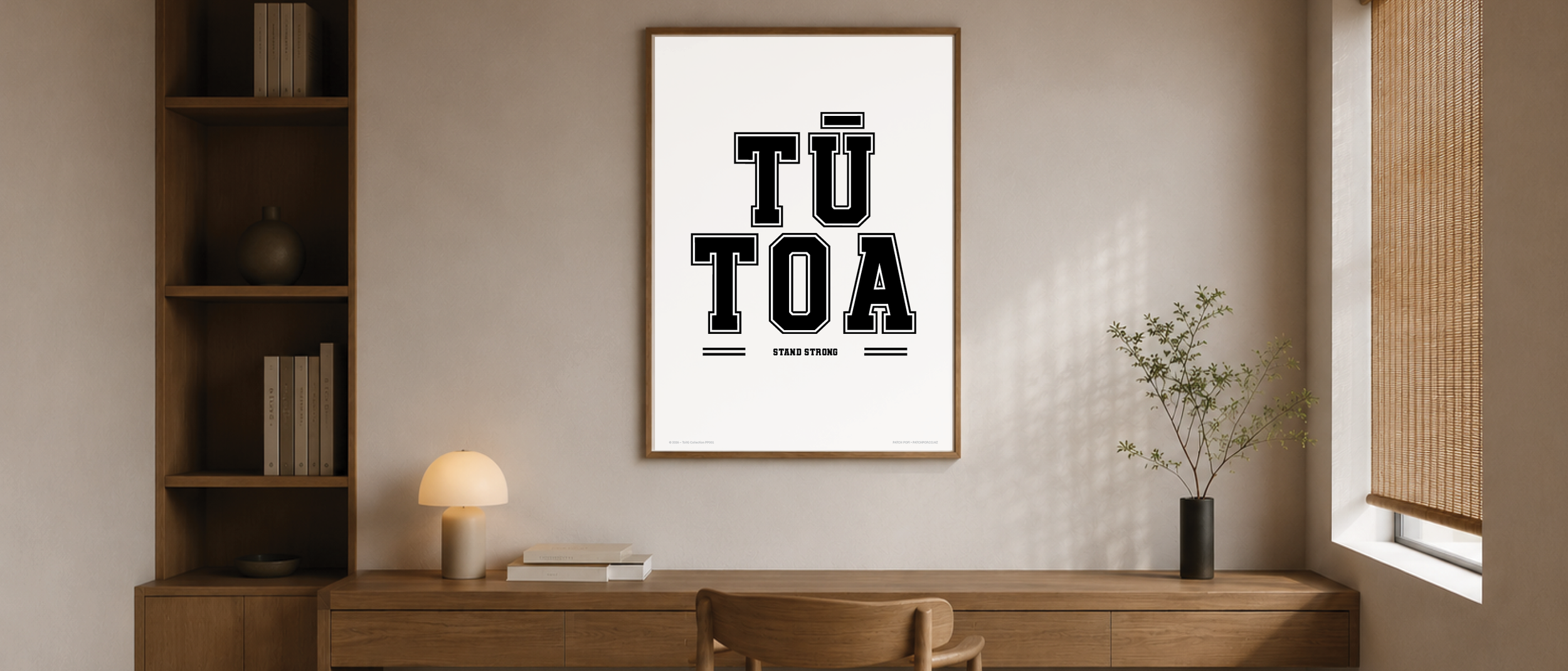 Interior room with a framed poster on the wall that reads 'TŪ TOA' and 'STAND STRONG' beneath. 