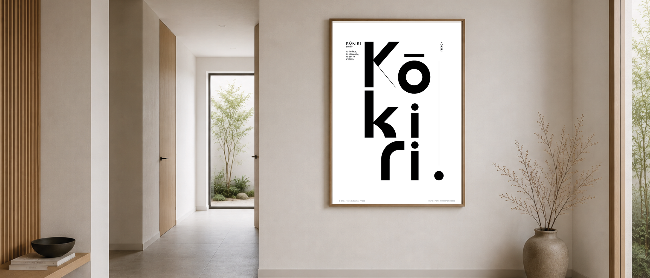 Modern hallway with a large framed poster featuring the word 'Kōkiri' in bold black letters on a white background, and a small definition text. There is a potted plant on a round ceramic pot on the floor near the wall, and a corner with vertical wood