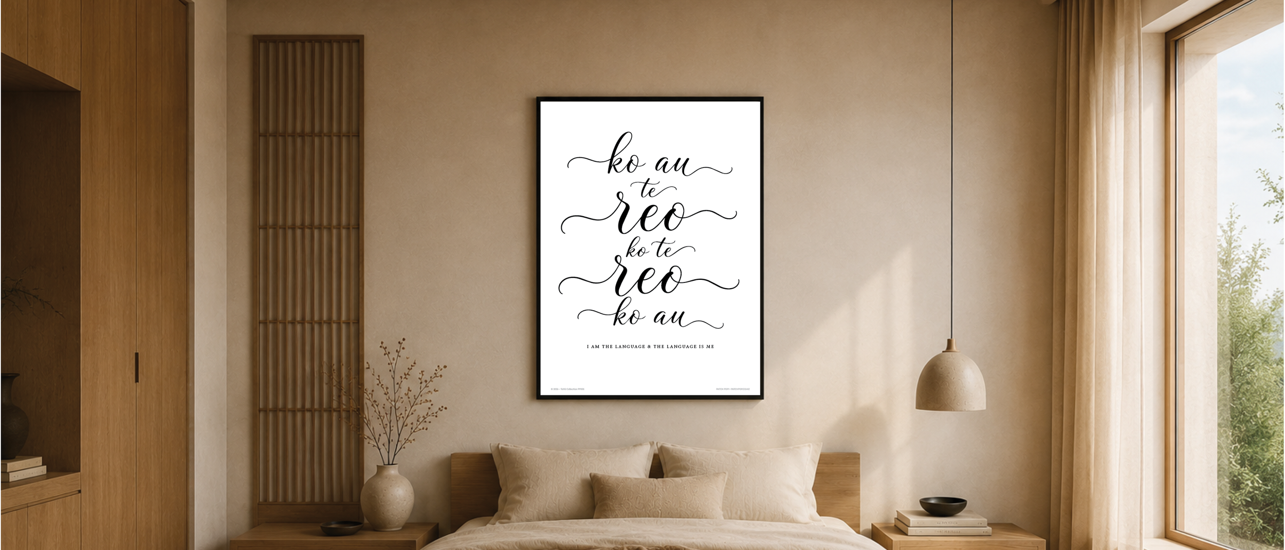 A modern bedroom with a large framed art print on the wall, featuring black cursive text that says 'ko au te reo' repeated twice and the phrase 'I am the language & the language is me' at the bottom. The room has wooden furniture, a beige bed with pi