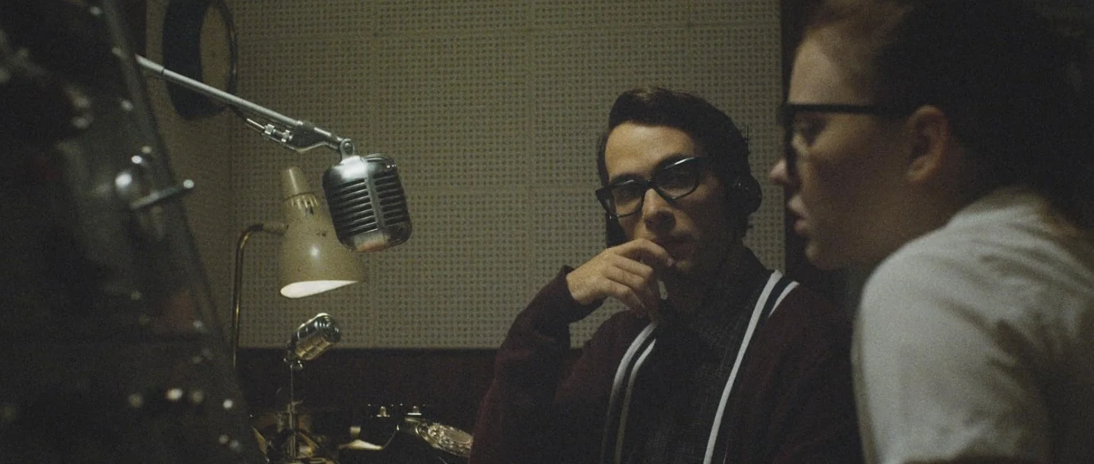 Film Still from the sci-fi drama film The Vast of Night (2019) featuring actors Sierra McCormick and Jake Horowitz in a radio station recording booth.