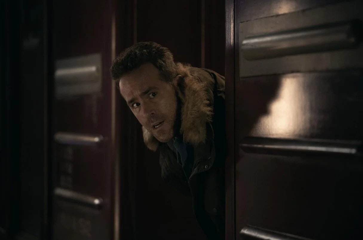 A man peeks out from behind a wooden train door, looking worried. This is a shot from the 2026 Apple TV film Mayday, starring Kenneth Branagh and Ryan Reynolds, written and directed by John Francis Daley and Jonathan Goldstein.