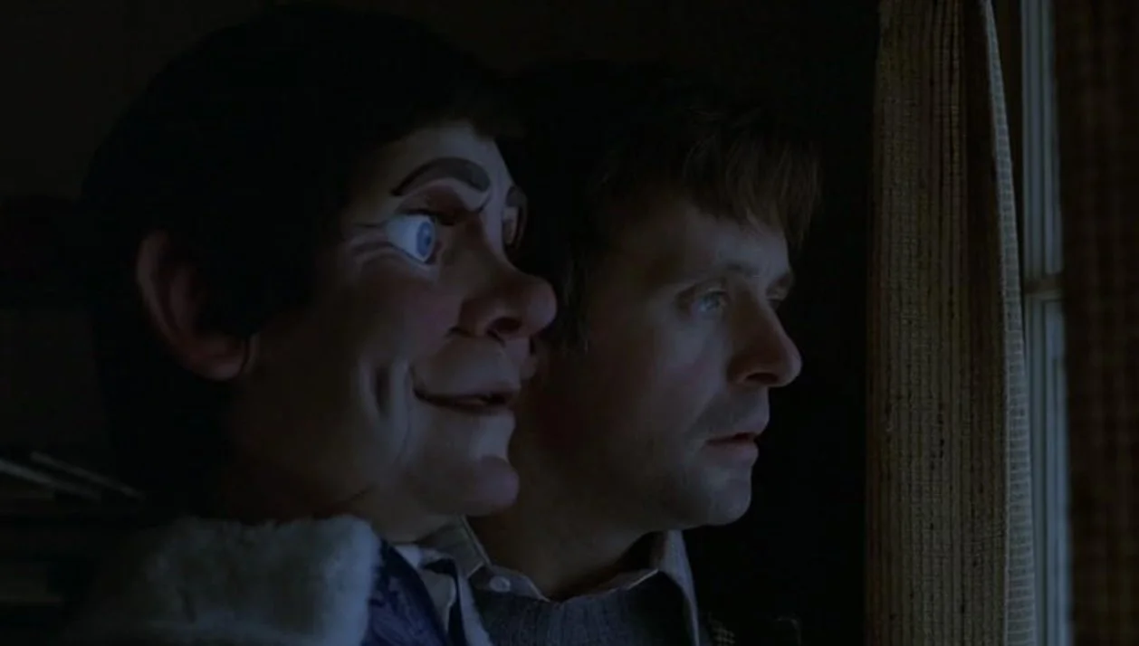 A man and his ventriloquist dummy look out a window at night, with dim lighting illuminating their faces. Magic (1978) directed by Richard Attenborough, written by William Goldman, stars Anthony Hopkins, Ann-Margret, Burgess Meredith.