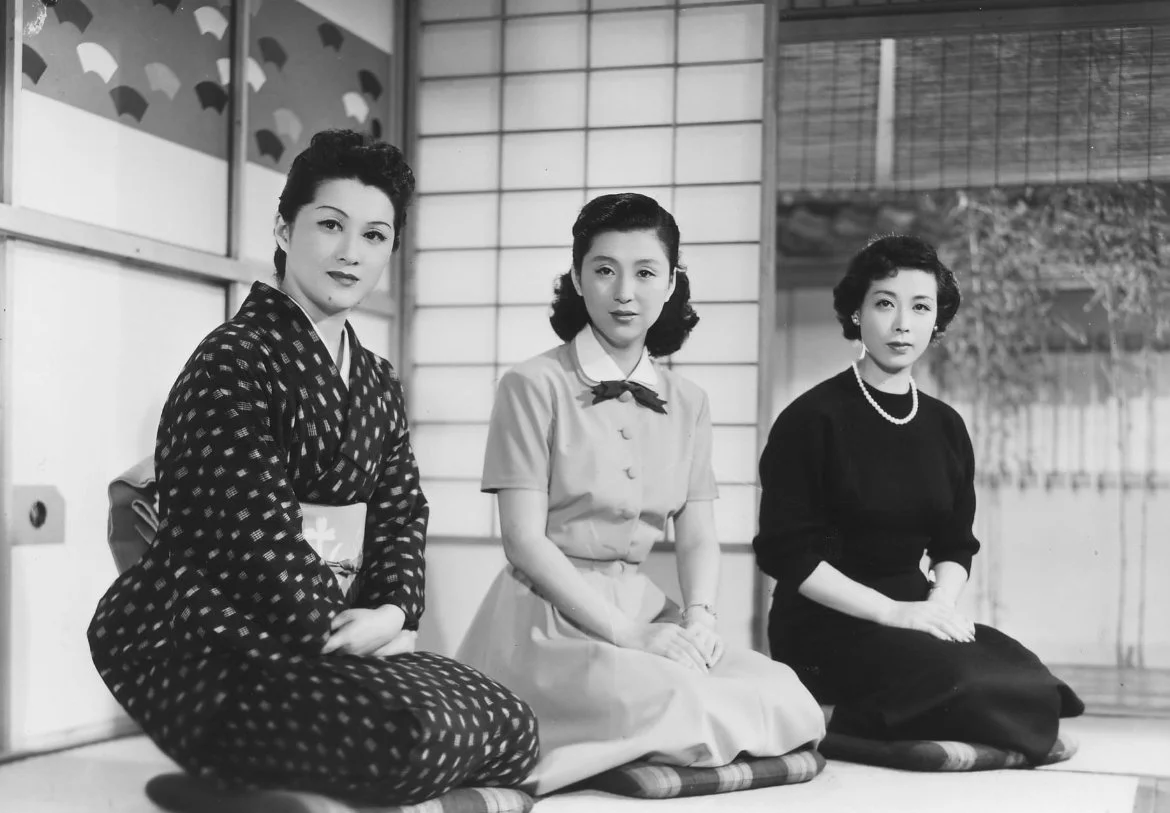 Three women sitting on cushions in a traditional Japanese room, dressed in vintage clothing and Kimonos, with a shoji screen. This is a scene from Ozu's The Flavour of Green Tea Over Rice.
