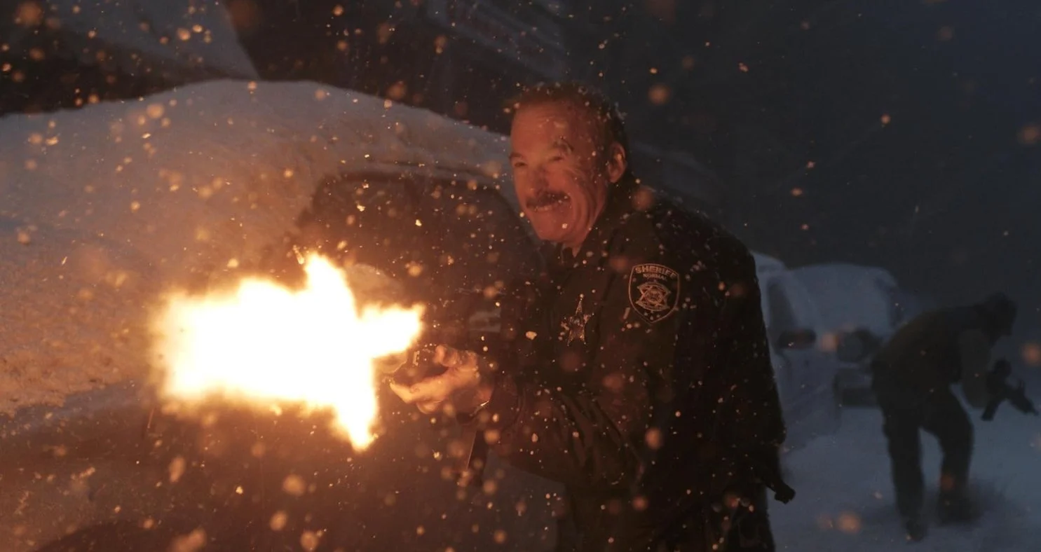 A firefighter in uniform fires a gun in a snowstorm at night, with snow and sparks flying around.