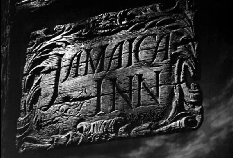 A black and white image of a carved wooden sign with the words 'Jamaica Inn' from the opening scene from the 1939 film Jamaica Inn with Charles Laughton and Maureen O'Hara.