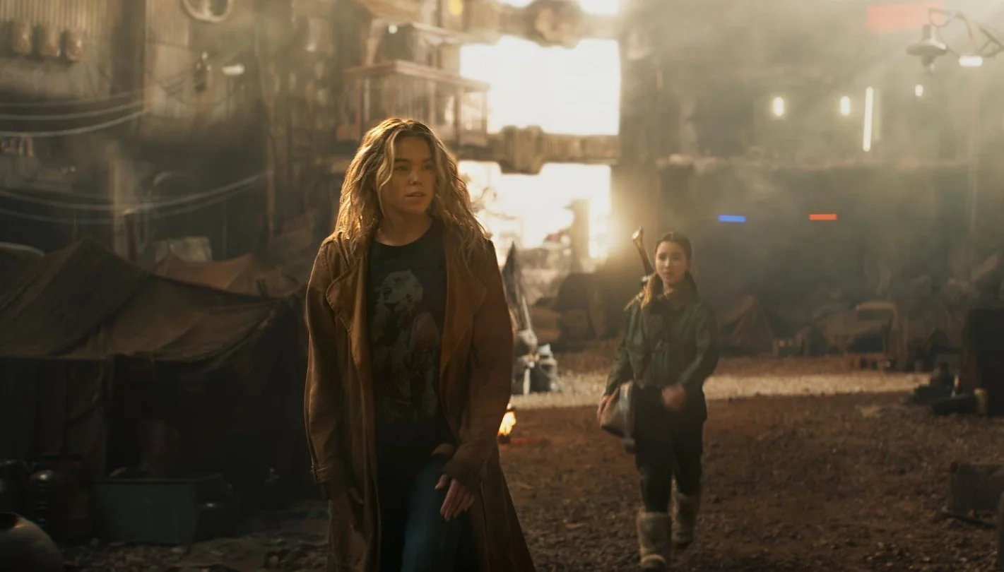 A still from the film Supergirl (2026) with Milly Alcock and Eve Ridley walking in town on another planet.