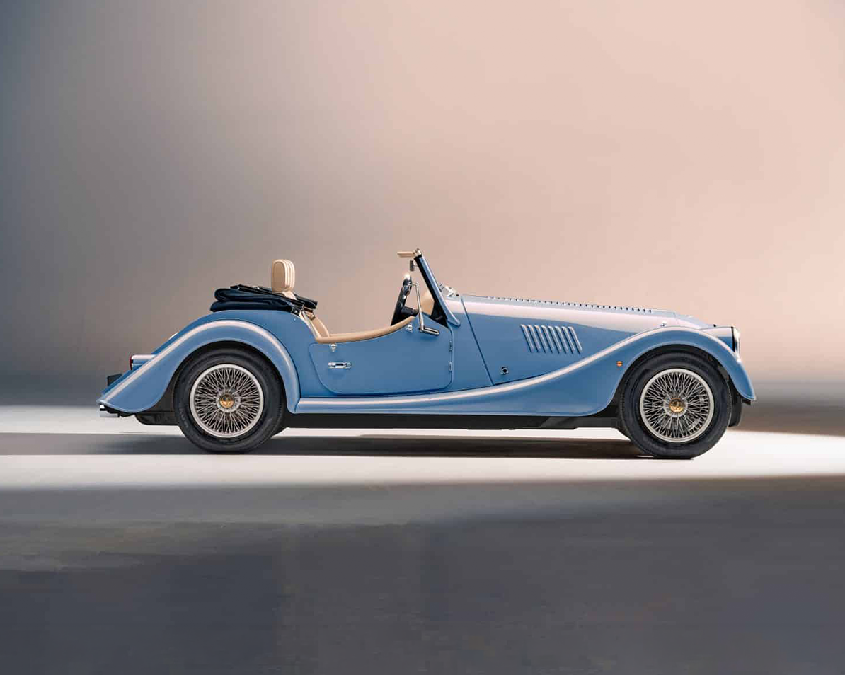 A vintage convertible car painted in light blue, parked on a smooth surface with a gradient beige background.