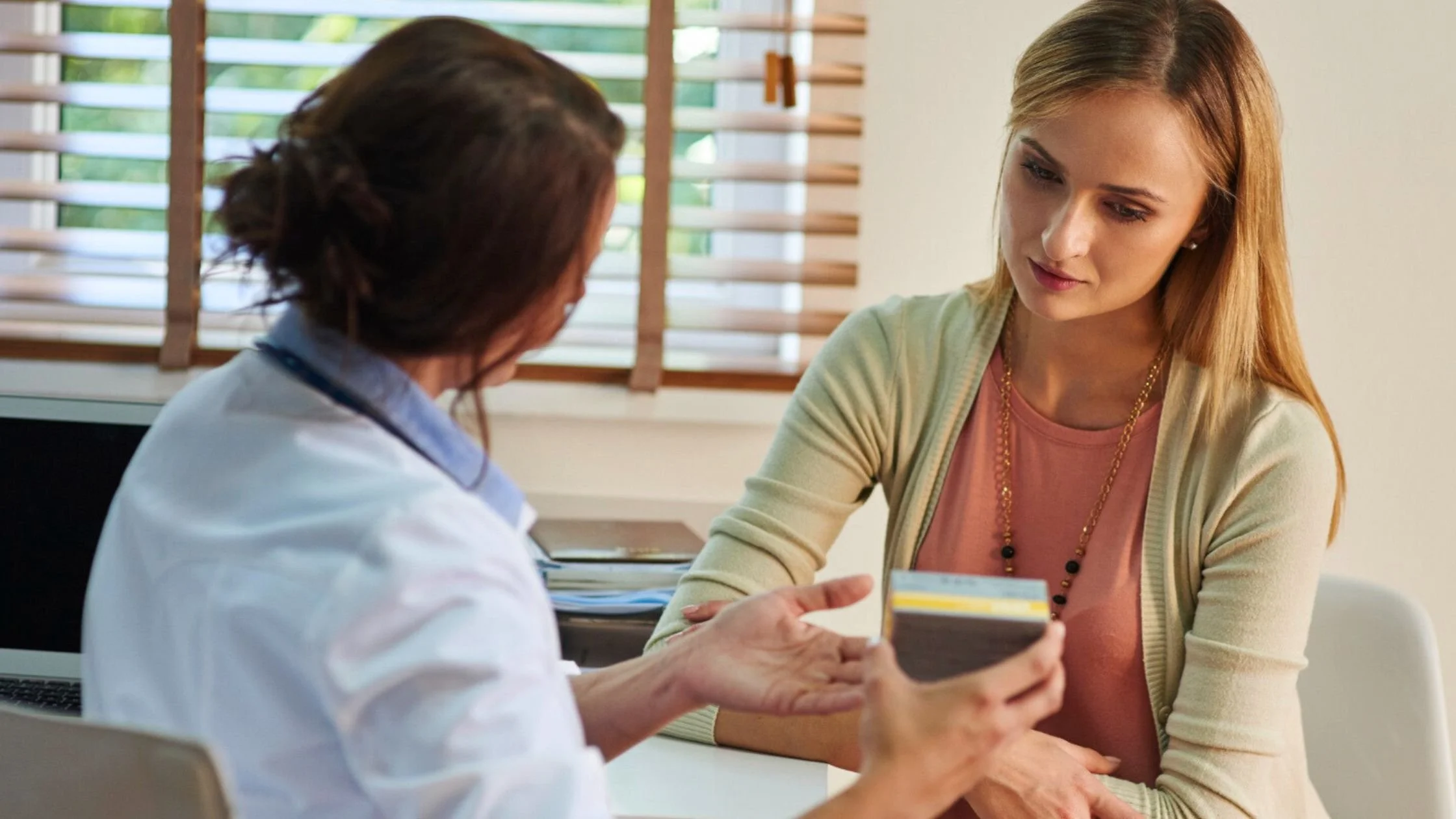 Two women in a professional consultation setting, representing the importance of routine well woman health screenings