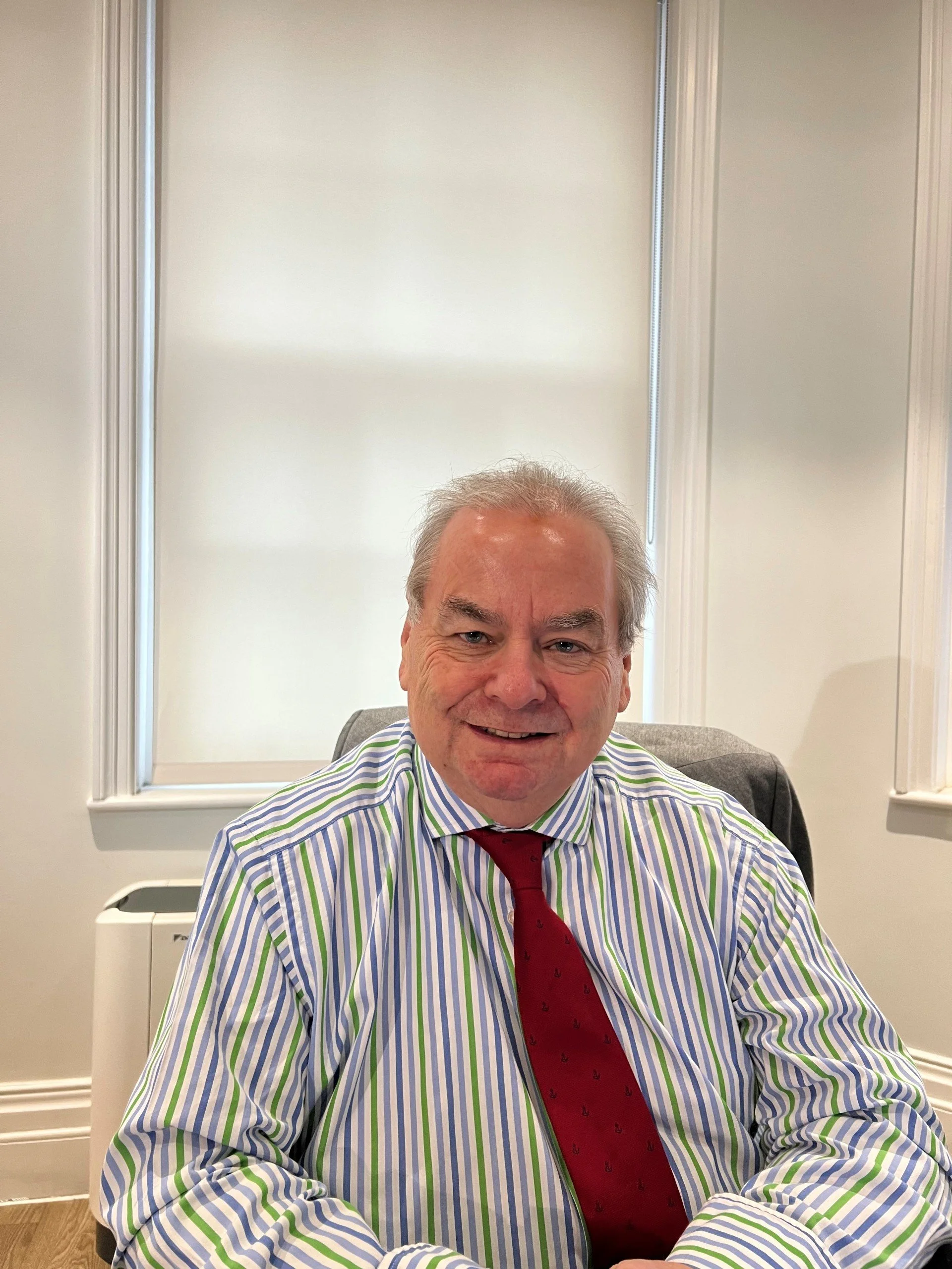 Mr Nicholas Morris MBBS FRCOG, Consultant Gynaecologist and Obstetrician, smiling in his consulting office