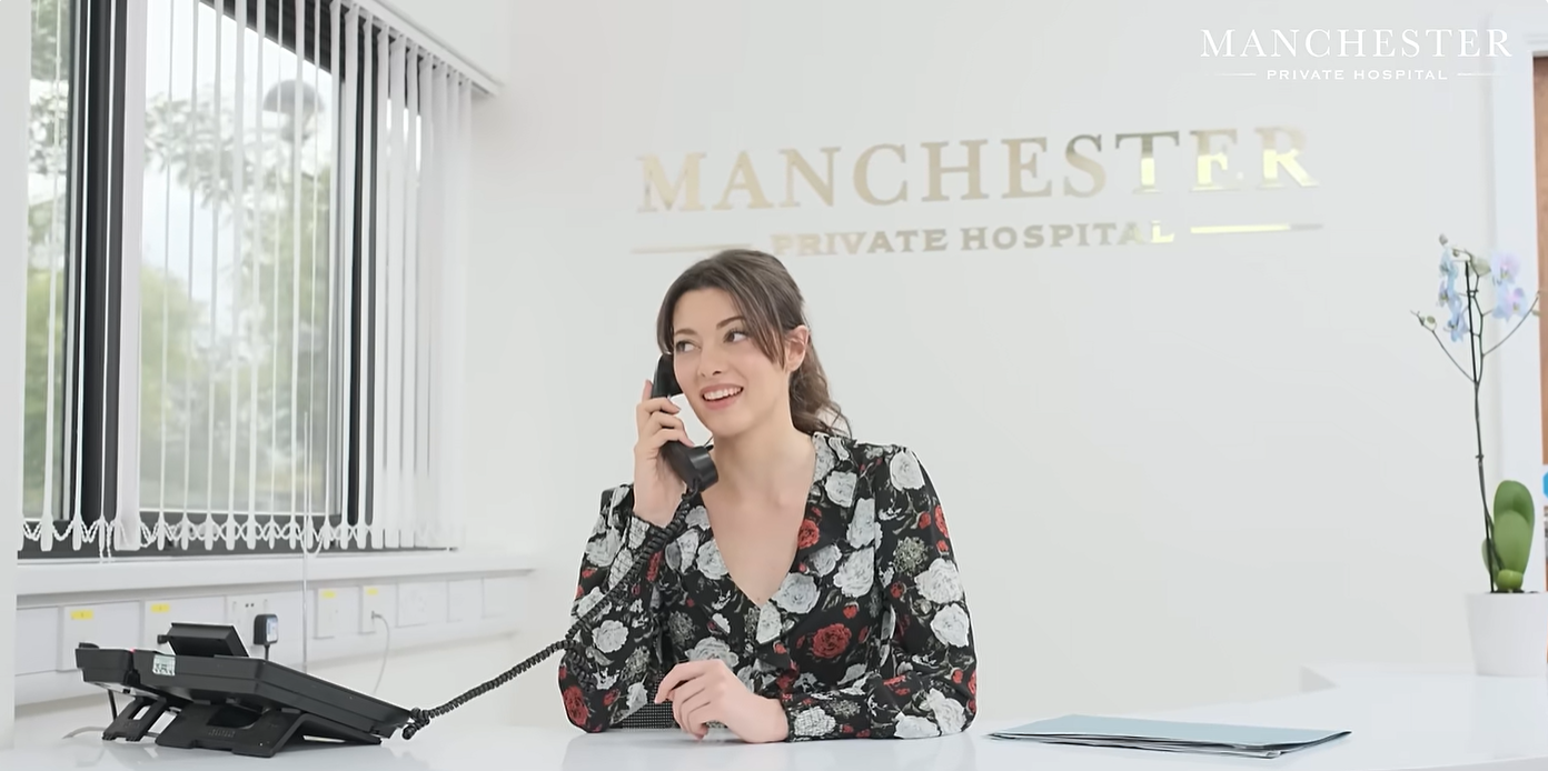 Friendly receptionist at Manchester Private Hospital assisting a patient by phone, reflecting the hospital's commitment to patient care