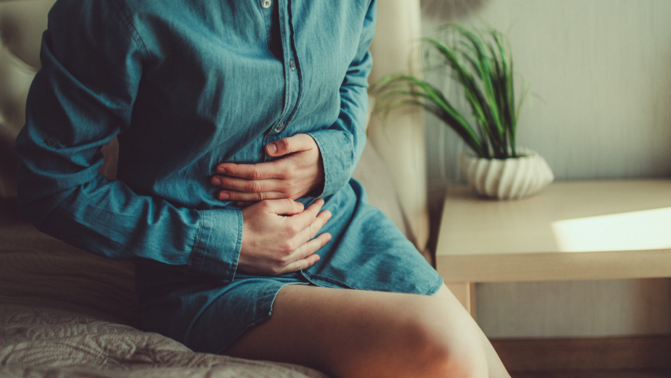 Woman holding lower abdomen considering if she has Dyspareunia 