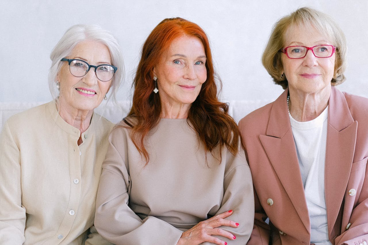Three older women smiling and posing together, representing wellness and women's health in later life