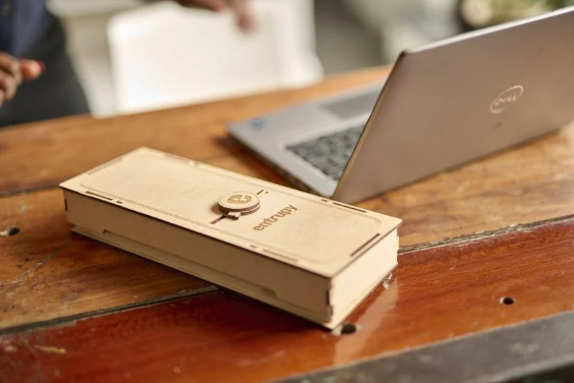 A cardboard box labeled 'Airtame' on a wooden table with a closed Dell laptop nearby.