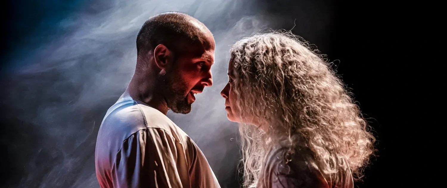 Två personer, en man och en kvinna, står nära varandra med ansiktena mycket nära, i ett emotionellt ögonblick.